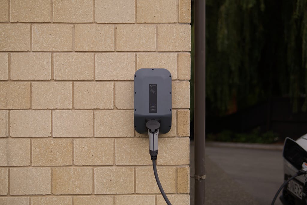 A wall-mounted electric vehicle charging station installed on a brick wall in Christchurch, New Zealand.
