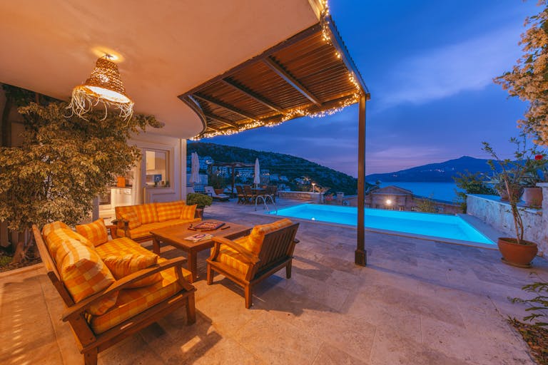 Elegant outdoor terrace with glowing pool and coastal views at dusk, perfect for relaxation.